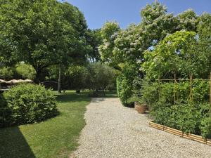 un jardin avec des buissons et des arbres et un chemin de gravier dans l'établissement Jonadam, à Saint-Julien-de-Lampon
