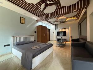 een slaapkamer met een bed, een bank en een televisie bij MUSHROOMS in Vasco Da Gama