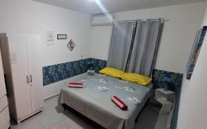 a small bedroom with a bed with yellow and red pillows at Pedacinho de Lar in João Pessoa