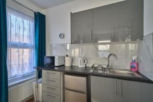 a kitchen with a sink and a microwave at Chapel Road Cosy Rooms & Studios in Hounslow