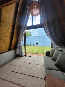 a living room with a couch and a large window at Hospedagem Chalés Prosas e Versos in Penha
