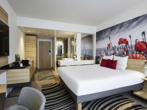 a hotel room with a large bed and a bathroom at Novotel Ieper Centrum in Ypres +59 photos