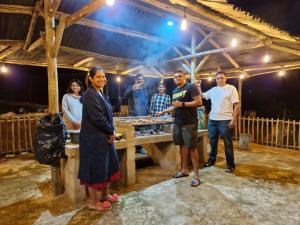 a group of people standing around a wooden table at Ashley's Cottage in Himeville
