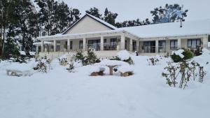 a house covered in snow in front of it at Ashley's Cottage in Himeville +6 photos