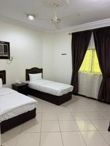 a hotel room with two beds and a window at شقة مفروشة بحي النسيم in Mecca