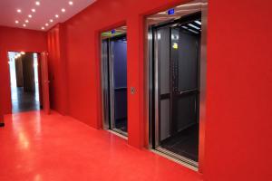 an empty corridor with red walls and glass doors at BA Millenium in Buenos Aires