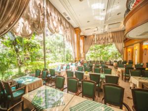 埔里鎮的住宿－鎮寶大飯店，用餐室配有桌子和绿色椅子
