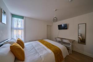 a bedroom with a large white bed and a desk at Chapel Road Cosy Rooms & Studios in Hounslow