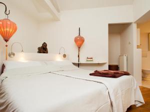 a bedroom with a large white bed with orange lamps at Hövell in Huizen