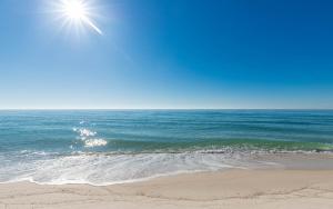 a beach with the sun shining over the ocean at Phoenix X 504 in Orange Beach