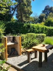 a wooden picnic table and bench in a garden at Tierras del Sur I un calido lugar in Villa La Angostura