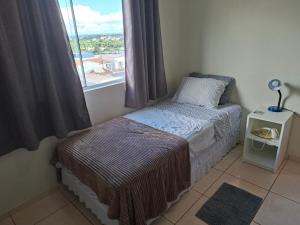 a small bedroom with a bed and a window at Apart próximo a Unimed, Catedral, HSA com 2 Ar e garagem in Santo Ângelo