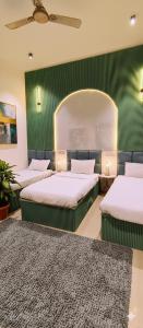 drie bedden in een kamer met een groene muur bij Hotel vk palace completly family stay #neartaj#luxurystay in Agra