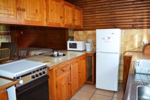 a kitchen with wooden cabinets and a white refrigerator at Log Cabin & Settlers Village in Graskop
