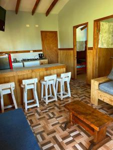 eine Küche mit einer Bar mit Hockern und einem Tisch in der Unterkunft Cabaña equipada a 5 minutos de Panguipulli in Huellahue
