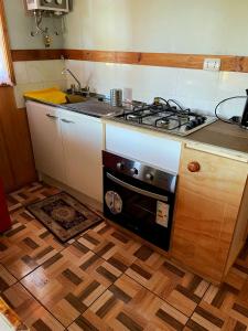 eine Küche mit Herd Top-Backofen neben einem Holzboden in der Unterkunft Cabaña equipada a 5 minutos de Panguipulli in Huellahue