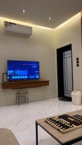 een woonkamer met een flatscreen-tv en een tafel bij Supreme suites in Al Kharj