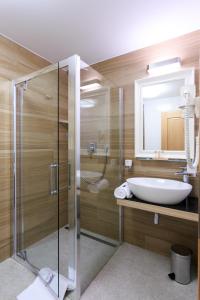 a bathroom with a glass shower and a sink at Hotel a restaurace U Vychopňů in Vsetín