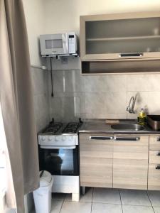 a kitchen with a stove and a microwave at Kitnet centro de bombinhas in Bombinhas