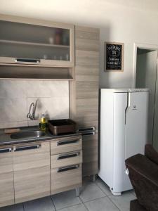 a kitchen with a white refrigerator and a sink at Kitnet centro de bombinhas in Bombinhas
