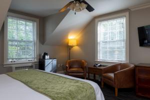 una camera da letto con un letto, una sedia e due finestre di Sherwood Inn a Port Carling