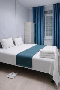 ein Schlafzimmer mit einem großen weißen Bett mit blauen Vorhängen in der Unterkunft Aerodrom Hotel - Hostel in Almaty + 18 Fotos