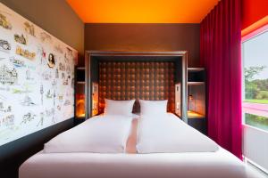 فندق ديزاين + مركز المؤتمرات فينيكي XI. في هانوفر: غرفة نوم بسرير وملاءات بيضاء وستائر حمراء