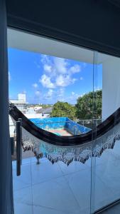 een raam met uitzicht op een zwembad bij Triplex Carapibus Beach in João Pessoa