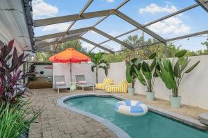 a swimming pool with an umbrella and a patio with chairs and an umbrella at The Art Deco Den in Tampa