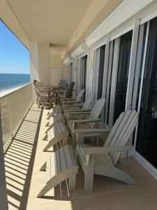 een rij stoelen op een balkon met uitzicht op het strand bij Beachfront Penthouse w Gulf & Bay Views in Gulf Highlands