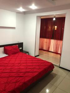 un grande letto rosso in una stanza con finestra di Central suite a Piteşti