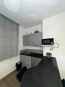 una cucina con pareti bianche e piano di lavoro nero di Studio confortable pour 2 personnes a Saint-Omer Altre 2 foto