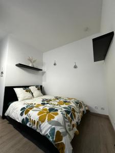 una camera da letto con un letto con copriletto floreale di Studio confortable pour 2 personnes a Saint-Omer Altre 2 foto