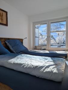 ein Bett in einem Schlafzimmer mit zwei Fenstern in der Unterkunft Spatz am Joch Zeit für Berge in Bad Hindelang