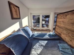 Bett mit blauen Kissen in einem Zimmer mit Fenster in der Unterkunft Spatz am Joch Zeit für Berge in Bad Hindelang