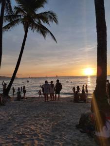 a group of people walking on the beach at sunset at RenSea Haven Boracay Rm10 in Boracay
