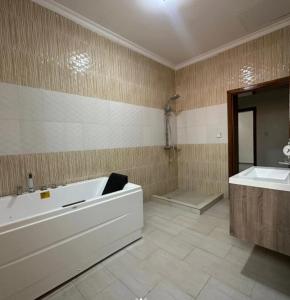 une grande salle de bain avec une baignoire et un lavabo dans l'établissement Peace Haven Apartment, 