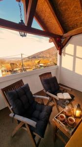 zwei Stühle und ein Tisch auf einer Veranda mit Aussicht in der Unterkunft Casa de sub Brazi Relaxare la munte cu Ciubar in Fîntînele