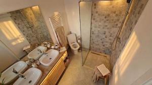 ein Badezimmer mit zwei Waschbecken, einer Dusche und einem WC in der Unterkunft Casa de sub Brazi Relaxare la munte cu Ciubar in Fîntînele + 92 Fotos