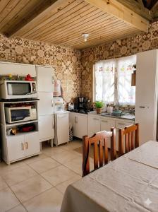 een keuken met witte apparatuur en een tafel in een kamer bij Casa Rústica em Garopaba in Garopaba