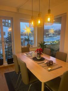 a dining room with a table with chairs and lights at Sentrumsnær leilighet Bergen in Bergen