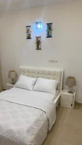 アビジャンにあるRésidence Alphadisの白いベッド1台、壁に3枚の絵が飾られたベッドルーム1室