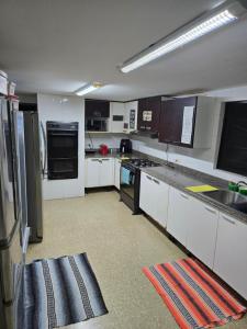 una cucina con mobili bianchi ed elettrodomestici neri di CulturaHumana Guesthouse a Città di Panama