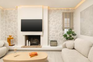 a living room with a couch and a tv at Seaview Garden Villa - Heated Pool & Sauna in Stalos