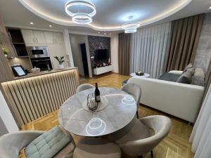 a dining room and living room with a table and chairs at Apartman Lux Jocić in Vrnjačka Banja