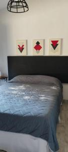 a bed in a bedroom with paintings on the wall at La Casita de Lucía in Almafuerte