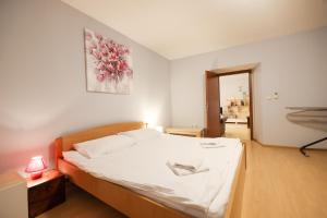 a bedroom with a large bed with white sheets and a lamp at Quattro Cantoni Apartment in Zadar