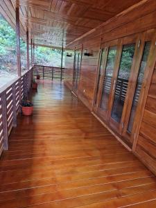 een lege gang van een blokhut met houten vloeren en ramen bij Ké San Gélica in São Tomé