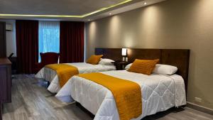 a hotel room with two beds with orange and white sheets at Hotel Imperial Saltillo in Saltillo +26 photos