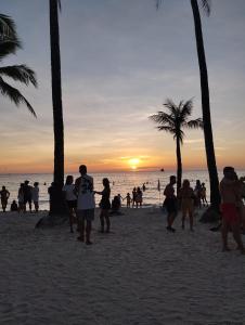 a group of people walking on the beach at sunset at RenSea Haven Boracay Rm10 in Boracay +6 photos